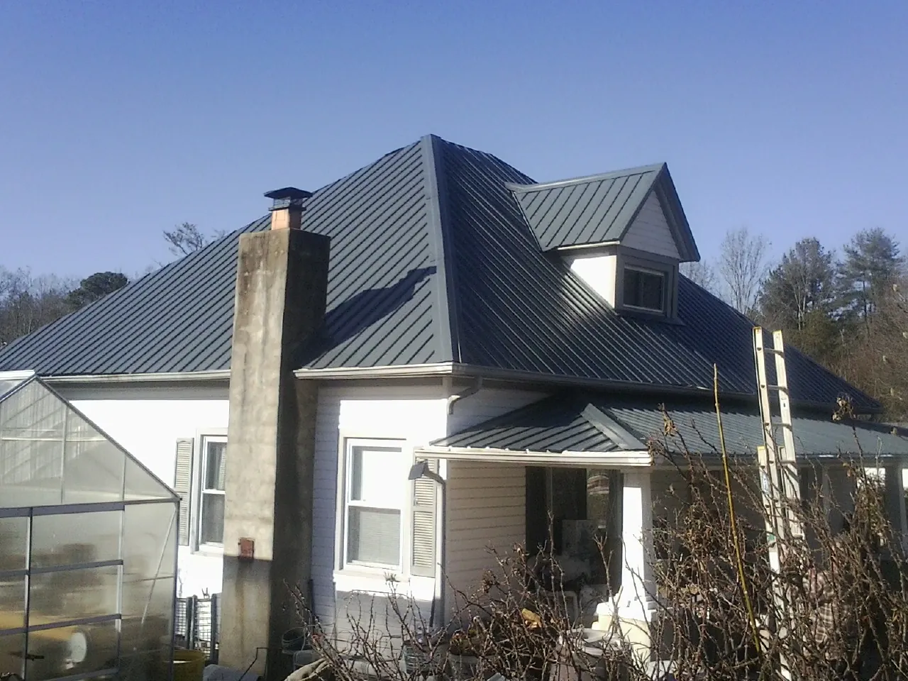 Dark blue standing seam metal roof on a white farmhouse with dormer — Slate & Tile Roof Repair by Roofing Brothers in Mount Vision