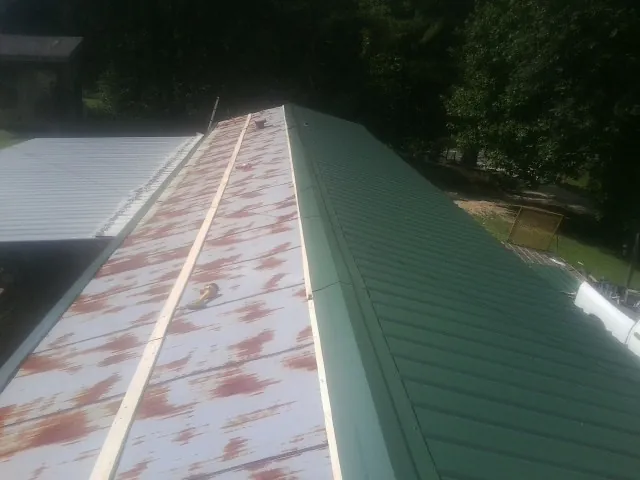 Old rusted panels beside newly installed green metal roofing — Wind Damage Roof Repair by Roofing Brothers in Mount Vision