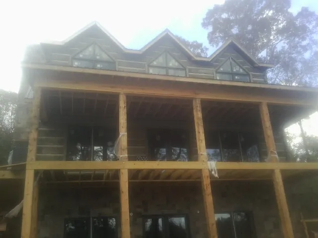 Dormers and porch framing on a large log home under construction — Roof Coating work by our crew in Mount Vision