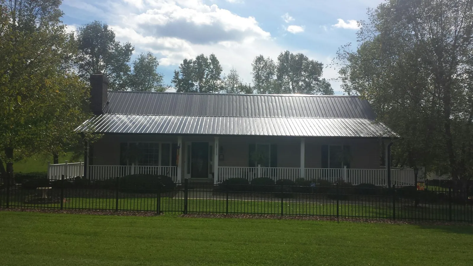 Gray metal roof on a brick ranch with a full width front porch — Gutter Guard Installation work by our crew in Mount Vision